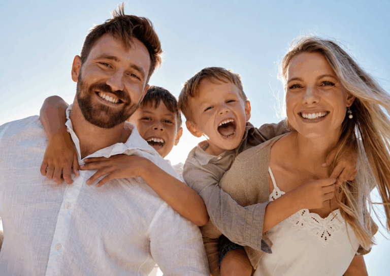 Smiling family of four enjoying time together outdoors on a sunny day.
